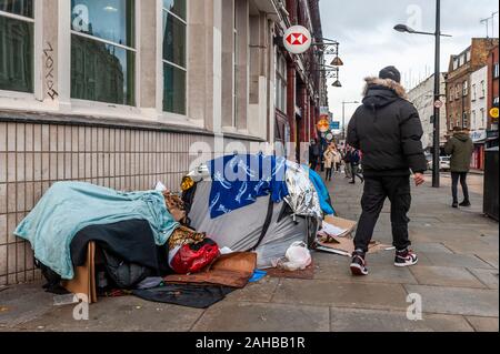 Menschen passieren das provisorische Zelt eines Obdachlosen vor der HSBC Bank in Camden Town, London, Großbritannien. Stockfoto