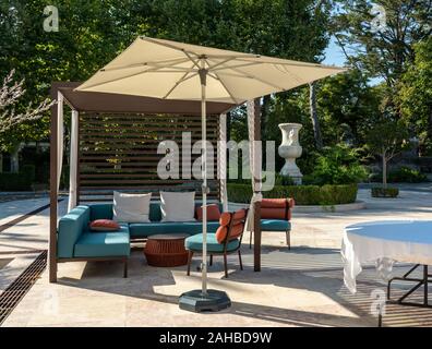 Moderne Gartenmöbel mit Sonnenschirm auf Marmor gepflasterten Hof oder Patio Stockfoto