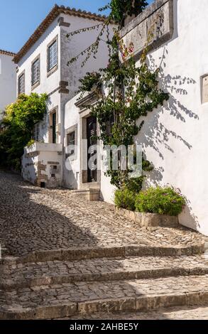 Steile Strasse mit Häusern in die mittelalterliche Festungsstadt Obidos in Portugal Stockfoto