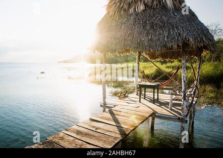 Bei Sonnenuntergang mit Sun Beam Hintergrundbeleuchtung am See Itza, El Remate, Peten, Guatemala Dock Stockfoto