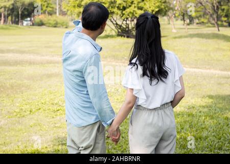 Asiatische Paare werden aufgezeigt und Aufmerksamkeit auf etwas im Garten zahlen. Asiatische Paare halten sich an den Händen und im Park. Nach männlichen und weiblichen Cou Stockfoto