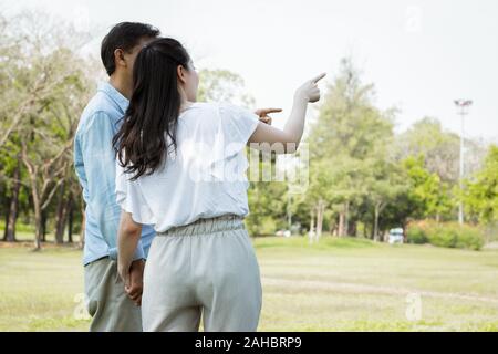 Asiatische Paare werden aufgezeigt und Aufmerksamkeit auf etwas im Garten zahlen. Asiatische Paare halten sich an den Händen und im Park. Nach männlichen und weiblichen Cou Stockfoto