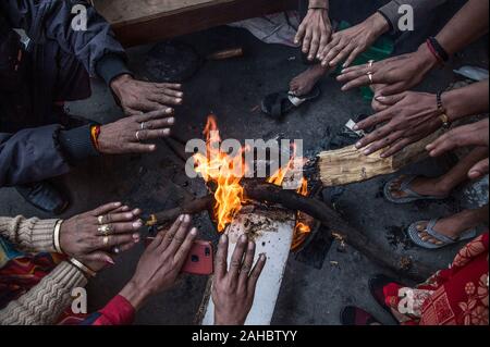 New Delhi, Indien. 27 Dez, 2019. Menschen warm sich in der Nähe ein Feuer in einer kalten Morgen in Neu Delhi, Indien, Dez. 27, 2019. Credit: Javed Dar/Xinhua/Alamy leben Nachrichten Stockfoto