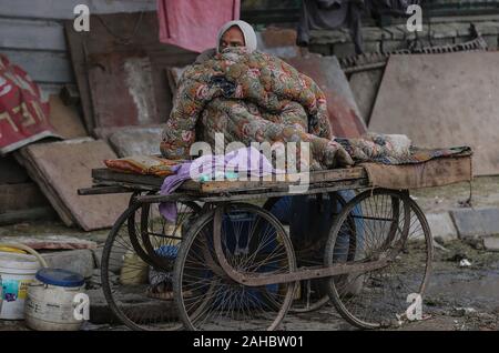 New Delhi, Indien. 27 Dez, 2019. Ein Mann wickelt sich in einem Quilt, wie er auf einem Wagen an einem kalten Morgen in New Delhi, Indien, Dez. 27, 2019 sitzt. Credit: Javed Dar/Xinhua/Alamy leben Nachrichten Stockfoto