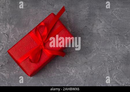 Roter Geschenkbox auf grauem Beton Hintergrund, kopieren. Geburtstag, zum Valentinstag, Muttertag und Frauentag Konzept. Nach oben Schließen Stockfoto