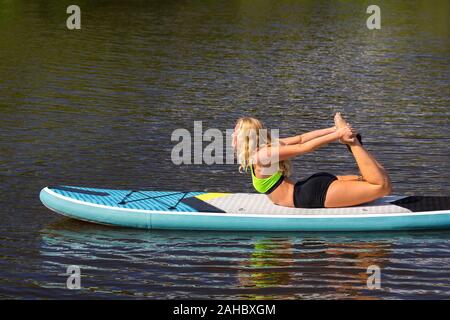 Blond kaukasische Frau yoga Körperhaltung auf SUP im Fluss Stockfoto