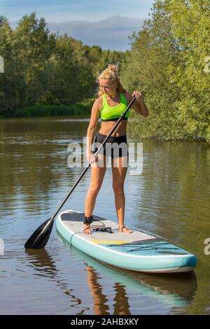 Ständigen junge holländische Frau Plattenelektroden mit SUP auf dem Wasser des Sees Stockfoto