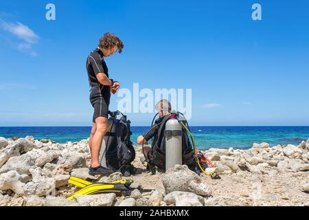 Zwei junge holländische Taucher am Strand Vorbereitung auf einen Tauchgang bei Bonaire Stockfoto