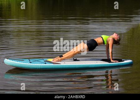 Junge kaukasier Frau rückwärts Beplankung auf paddle Board am See Stockfoto