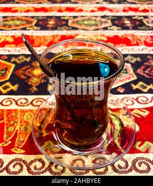 Ein Türkischer Pokal mit schwarzem Tee steht auf dem Tisch vor dem Hintergrund der Türkischen Ornament. Türkische Traditionen. Stockfoto