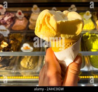 In einem weiblichen Hand, gelb Eis auf dem Hintergrund eines Zählers mit Eis. Für Text platzieren. Reisen. Stockfoto