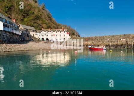 Das Red Lion Hotel im Hafenanglerdorf Clovelly mit Blick auf die Hafenmauer und ein rotes Fischerboot, North Devon, South West Stockfoto