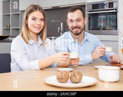 Glückliches junges Paar beim Gespräch über Tasse Kaffee in stilvollen Küche Innenraum Stockfoto