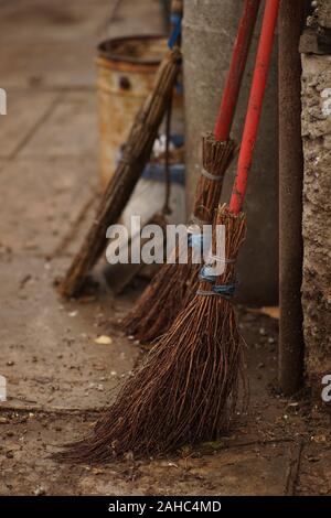 Satz von alten Wicker gestrickt Besen in einem feuchten ländlichen Hof. Stockfoto