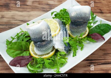 Rollmops mit gemischten Salat auf hölzernen Tisch Stockfoto