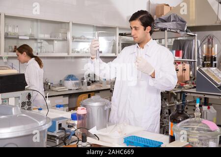 Junge männliche Chemiker im Labor arbeiten, die Analyse von flüssigen Proben in versuchsfläschchen Stockfoto