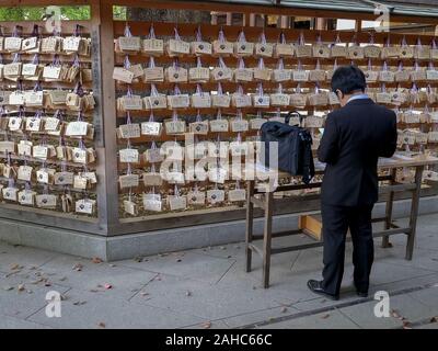 Tokio, Japan - April, 10, 2018: ein Mann schreibt auf einer Votivtafel in der Meiji Schrein in Tokio, Japan. Stockfoto