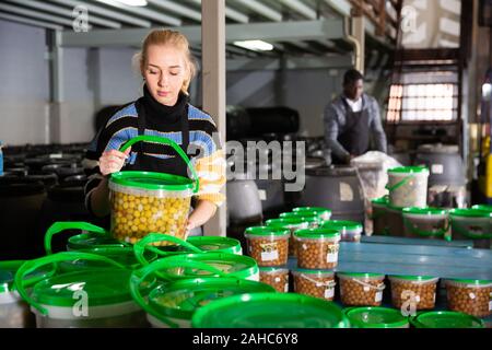 Weibliche Arbeitnehmer stocks Kunststoffbehälter und Dosen mit Oliven im Lager Stockfoto