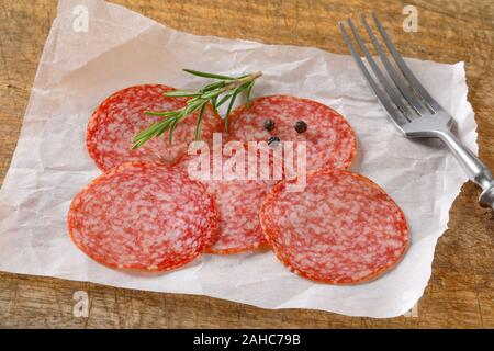 In Scheiben geschnittene Salami Wurst auf weißes Wachs Papier Stockfoto