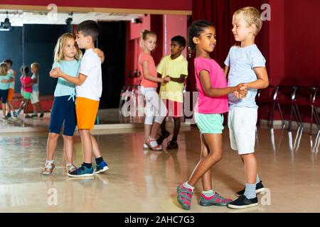 Lächelnde Kinder Grundschule versucht, Tanzen der Partner Tanz in Modern Dance Studio Stockfoto