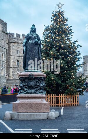 Bronze Statue von Queen Victoria steht außerhalb Schloss Windsor in Großbritannien mit einem Weihnachtsbaum hinter, Stockfoto