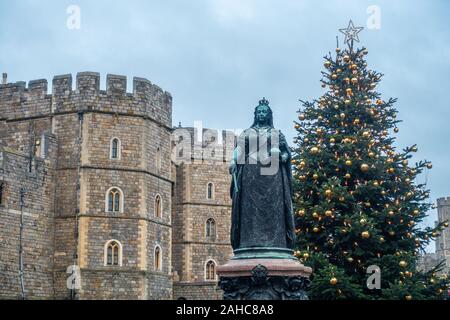 Bronze Statue von Queen Victoria steht außerhalb Schloss Windsor in Großbritannien mit einem Weihnachtsbaum hinter, Stockfoto