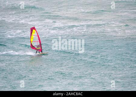 Ein Windsurfer skimming an Geschwindigkeit auf das Meer bei Crantock in Newquay in Cornwall. Stockfoto