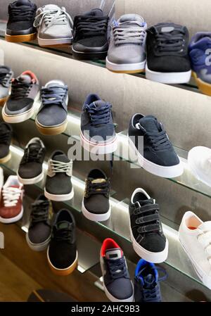 Viele moderne stilvolle Casual Shoes auf Regalen in Schuhgeschäft Stockfoto