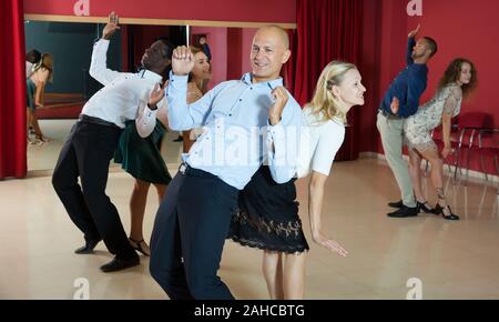 Junge lächelnde Menschen üben heftige jive Bewegungen im Tanz Klasse Stockfoto