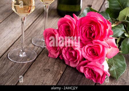 Nahaufnahme der Blumenstrauß aus Rosen und zwei Gläser Sekt auf Holzmöbeln im Landhausstil Oberfläche Stockfoto