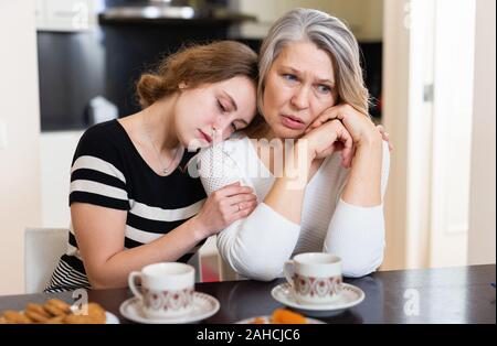 Junge Frau beruhigend ihre mirtarbeiter reife weibliche Freund über Tasse Tee zu Hause. Stockfoto