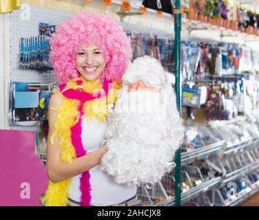 Porträt der jungen fröhliche Frau, die versucht, auf Rosa clown Perücke Stockfoto