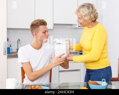 Ältere Mutter, white box Sie überrascht erwachsener Sohn in der Küche Stockfoto