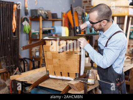 Qualifizierte Arbeiter polstern Stuhl in Reparatur Möbel Workshop Stockfoto