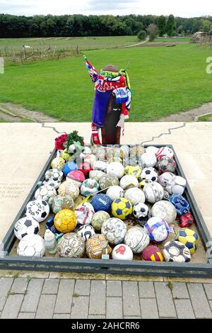 Die Leute gehen weg, Fußbälle und Club Andenken an die UEFA-Denkmal für die Weihnachten Waffenstillstand 1914 und Fußballspiele zwischen britischen und deutschen Soldaten Stockfoto