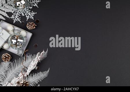 Weihnachten Zusammensetzung mit silbernen Ästen, christmas ball, Schneeflocken und Geschenk auf schwarzem Hintergrund. Neues Jahr Hintergrund schön Grußkarte. Stockfoto