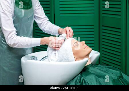 Friseur wickelt die Haare des Kunden in Handtuch nach dem Waschen Kopf in den Schönheitssalon. Stockfoto