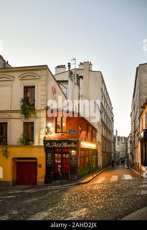 Blick auf eine Straße mit Kopfsteinpflaster im historischen Viertel Montmartre mit Le Petit Moulin, typischen Pariser Bistro, am Abend, Paris, Frankreich Stockfoto