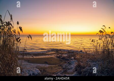 Die ersten Strahlen der Sonne über dem Ladogasee am Morgen im Winter. Region Leningrad. Stockfoto