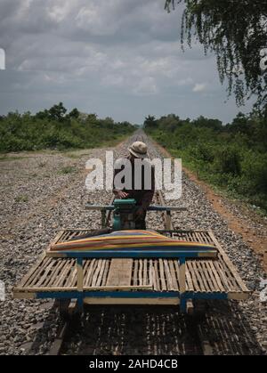 Kambodischer Führer mit Bambuszug und Meerbusbahnen im Hintergrund an einem sonnigen Tag, Battambang, Kambodscha Stockfoto