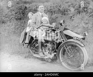 Ein edwardianisches Schwarz-Weiß-Vintage-Foto, das einen Mann zeigt, der auf einem Royal Enfield Motor Bike, Registrierungsnummer, ihr da 4595, mit seiner jungen Bucht auf dem Benzintank vor ihm sitzt, und seiner jungen Tochter, die hinter ihm sitzt. Irgendwo in England. Stockfoto