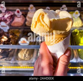 In einem weiblichen Hand, gelb Eis auf dem Hintergrund eines Zählers mit Eis. Für Text platzieren. Reisen. Stockfoto