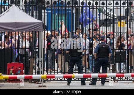 Touristen und Besucher, von bewaffneten Polizisten vor den Toren beobachtet, Downing Street, Westminster, London, UK Stockfoto