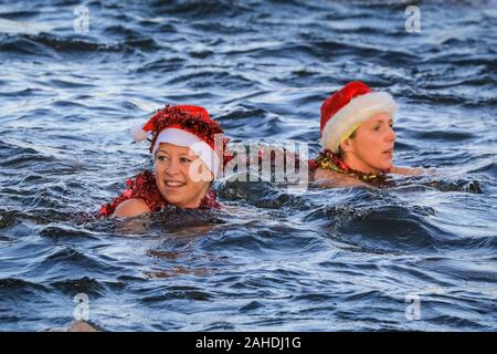 Weihnachtstag Schwimmer in Santa Hut schwimmen im kalten Wasser im Rennen um den "Peter Pan Cup', Serpentine Swimming Club, Hyde Park, London Stockfoto