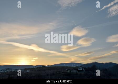 Schöne Wolken über der Kleinstadt in einem Tal. Von Tag zu Nacht. Himmel bei Sonnenuntergang in Banska Bystrica, Slowakei. Verdunkelter Himmel am Abend. Stockfoto