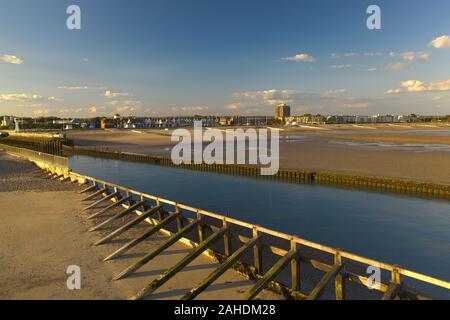 Blick auf den Fluss Arun in das Meer bei Ebbe mit Littlehampton im Hintergrund an einem schönen warmen Sommertag. Stockfoto