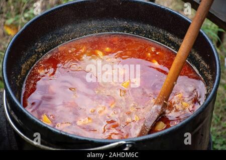 Kochen köstliches Kesselgulasch mit Treffen, Pfeffer, Tomaten, Zwiebel in einem großen Topf im Freien Stockfoto