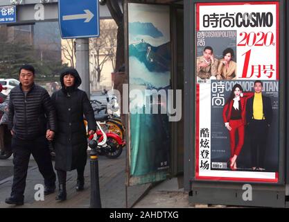 Peking, China. 28 Dez, 2019. Chinesische vorbei einen news Kiosk sowohl chinesische als auch internationale Magazine auf einer Straße in der Innenstadt von Peking Verkauf am Samstag, 28. Dezember 2019. American Lifestyle Zeitschriften, vor allem derjenigen, die sich mit westlichen Lebensstil, Promis und Mode in China sehr populär sind, mit den meisten ausländischen Zeitschriften in eine chinesische Version ihre Deckung der populären Kultur. Foto von Stephen Rasierer/UPI Quelle: UPI/Alamy leben Nachrichten Stockfoto