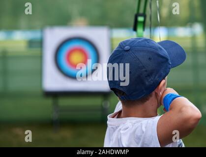 Junge zielt darauf ab, ein Ziel mit Pfeil und Bogen. Stockfoto