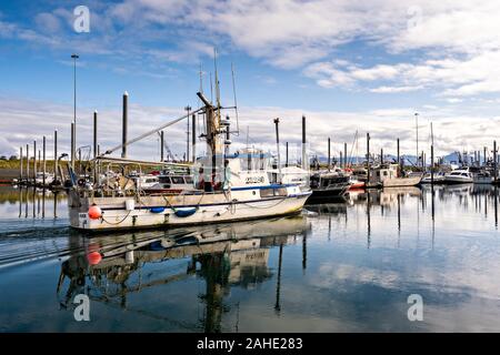 Eine kommerzielle Fischerboot Motoren durch die Stadt der Homer Port & Hafen Marina auf die Kachemak Bucht mit Blick auf die Kenai Mountains in Homer, Alaska. Stockfoto